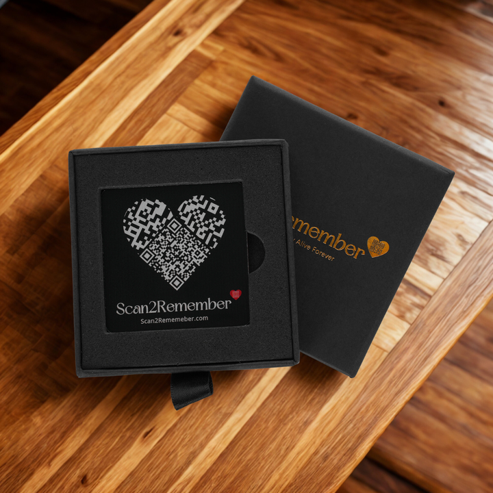 A black QR pet memorial plaque with a heart-shaped scannable code, shown in an open gift box.
